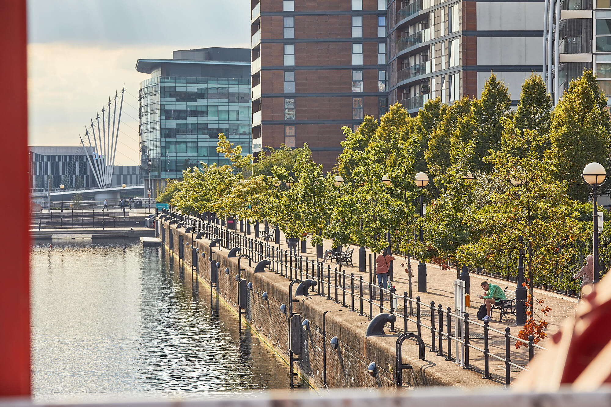 A person walking along a stretch of the Salford Quays waterfront canal