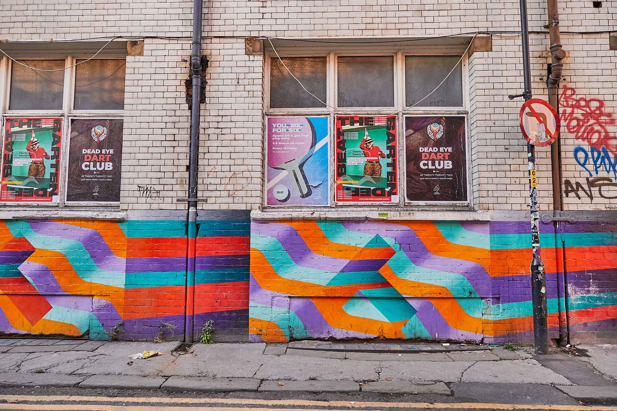 A busy highstreet in the northern quarter of manchester showing beautiful artwork on the side of the wall patterns