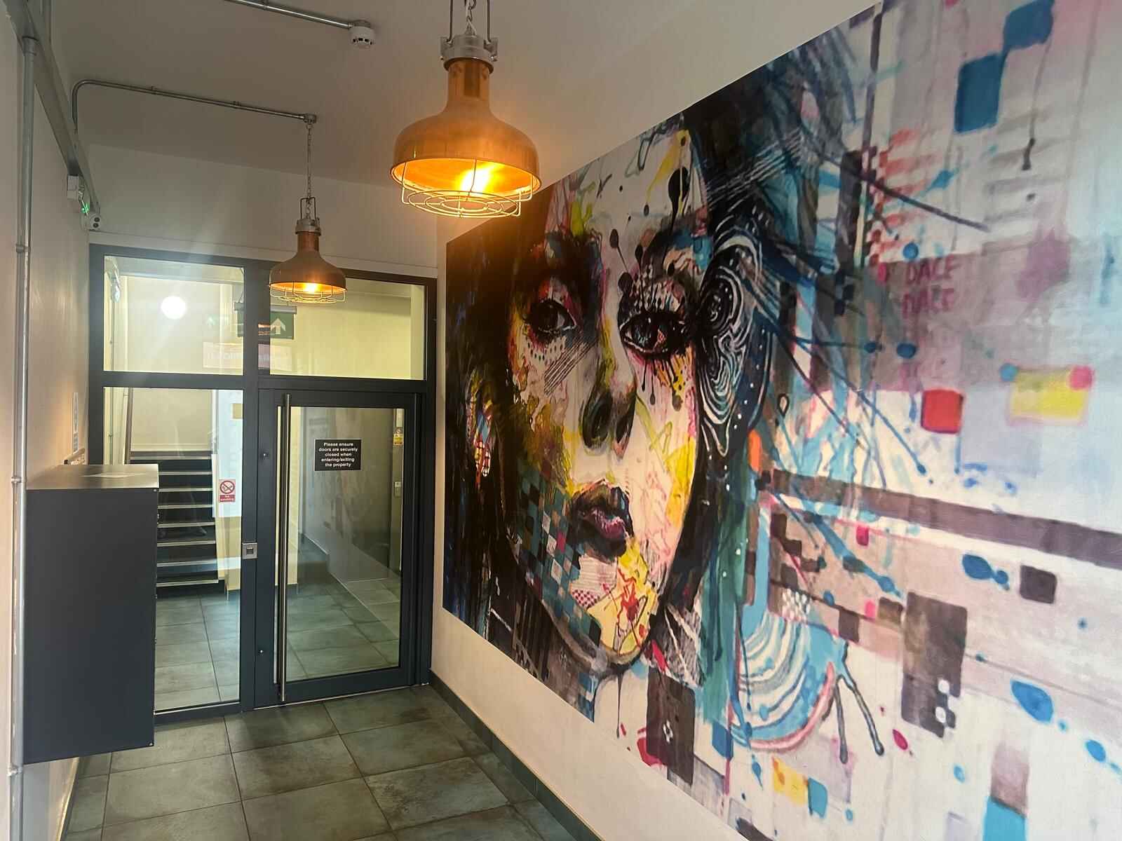 Entrance into POPworks with large artwork of a womens face painted with colours