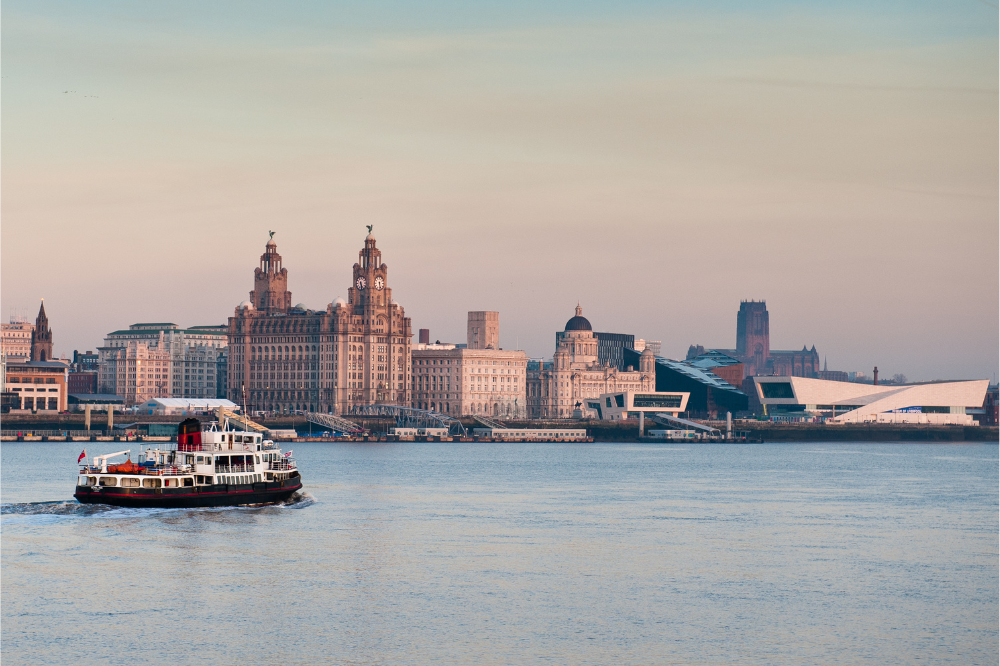 Lake overlooking the view of liverpool with boat in the middle and towered buildings in the distance
