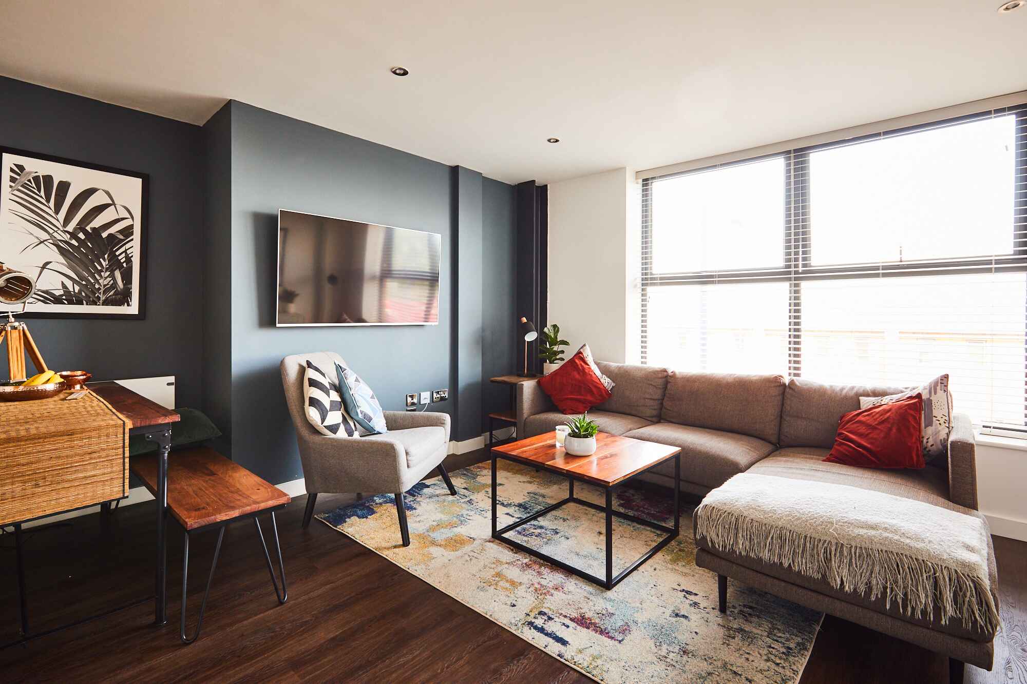 POPworks living room with corner sofa red pillows and a small square table in the middle