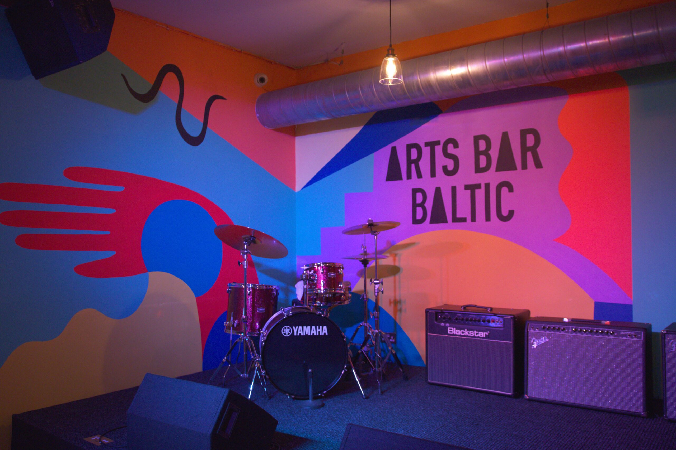 http://arts%20bar%20baltic%20sign%20on%20the%20wall%20drums%20in%20front%20and%20a%20speaker%20next%20to%20the%20drums