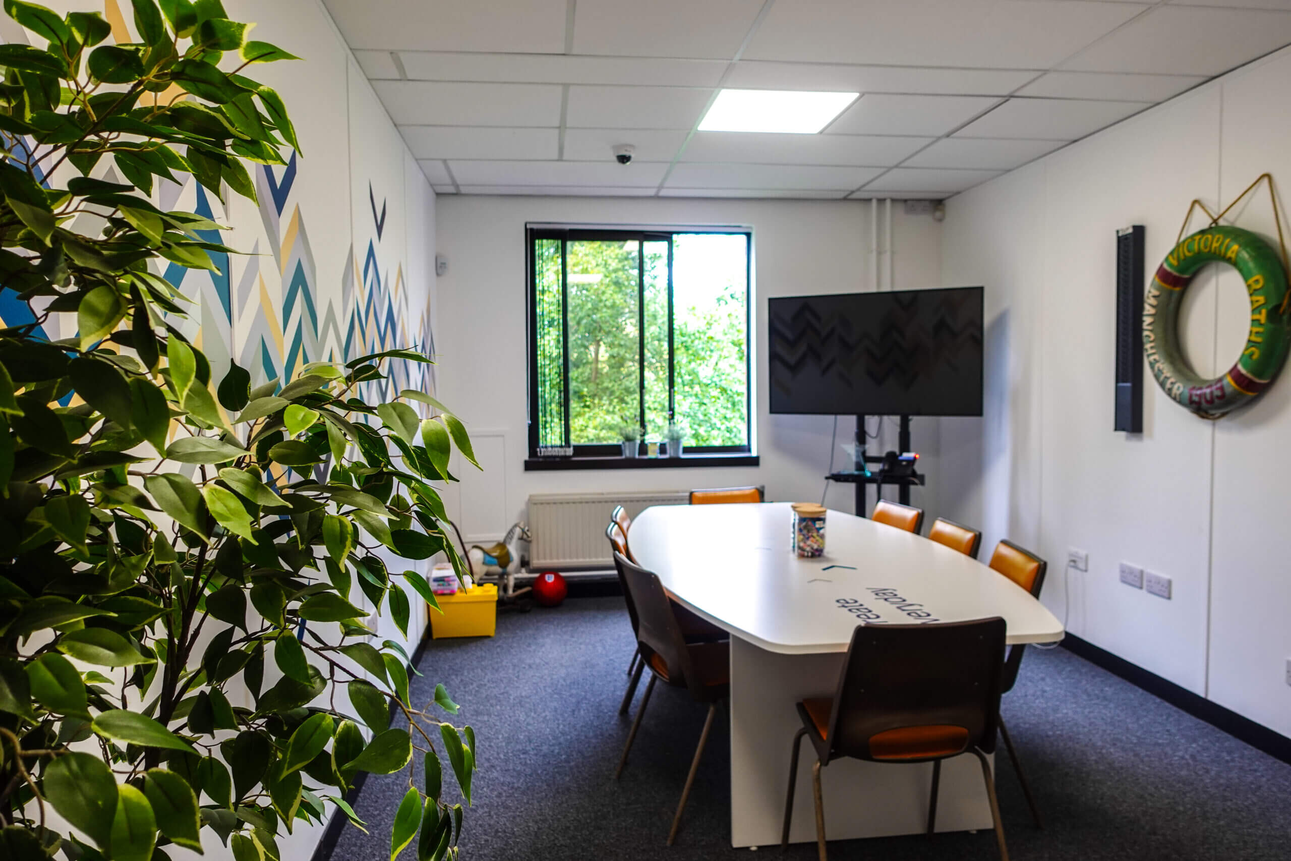 Salfords Quays The Junction meeting room space in the commercial offices with a boardroom table surrounded by 8 chairs and tv in the corner